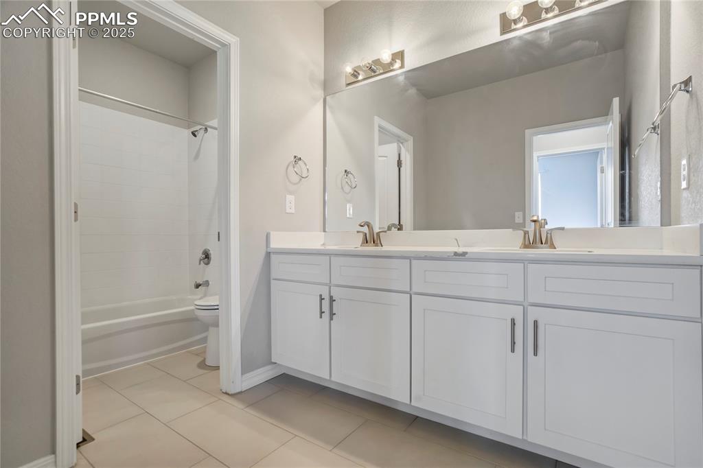 Image 26 of 44: Bathroom with light tile patterned flooring, double vanity, and bathtub / s