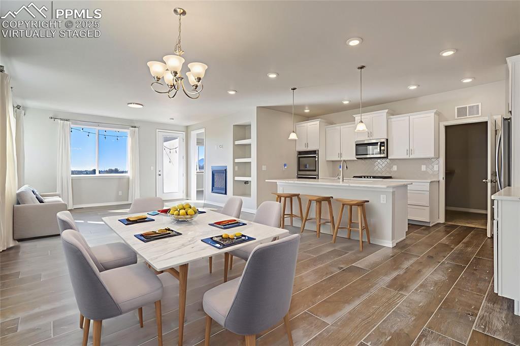 Image 3 of 44: Dining space with light wood-type flooring, built in shelves, a chandelier,