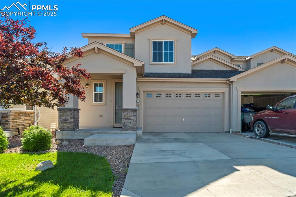 Image 38 of 44: View of front facade with stucco siding, driveway, covered porch, and stone