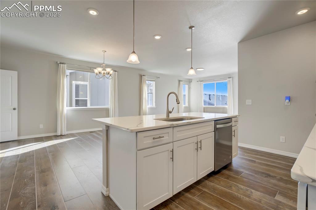 Image 5 of 44: Kitchen featuring dark wood-style flooring, light stone counters, white cab