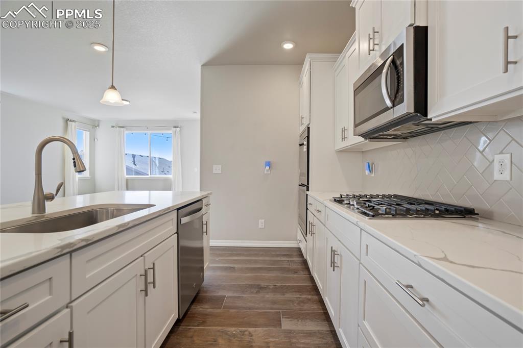 Image 6 of 44: Kitchen with white cabinetry, wood tiled floors, light stone countertops, h