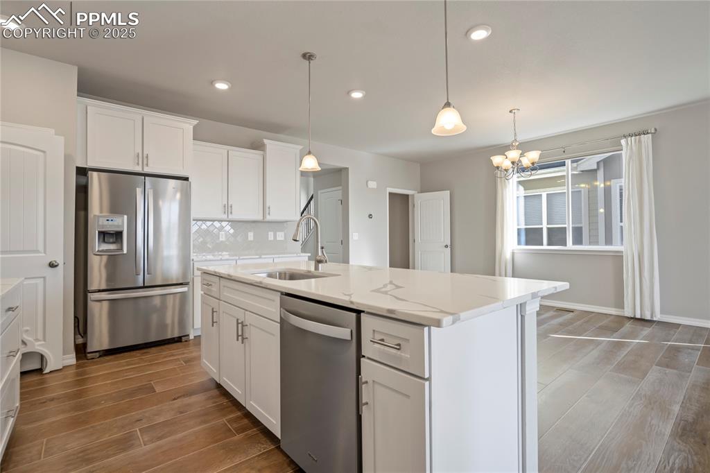 Image 8 of 44: Kitchen featuring stainless steel appliances, wood finish floors, white cab