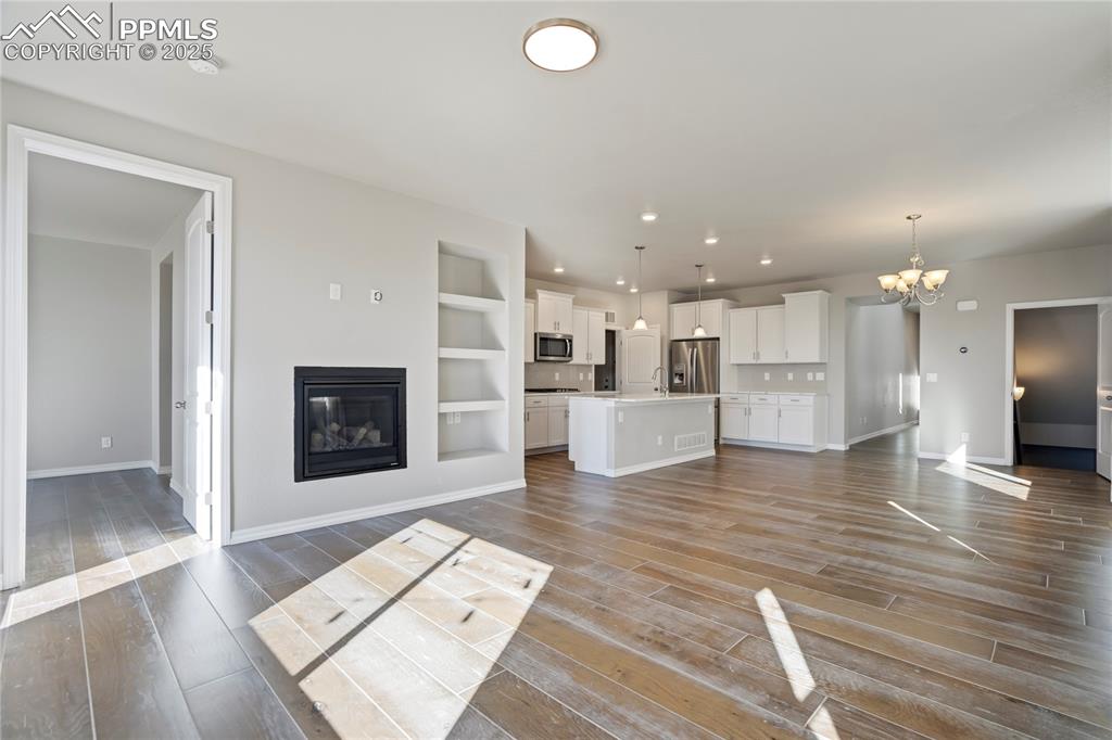 Image 9 of 44: Unfurnished living room with a glass covered fireplace, light wood finished