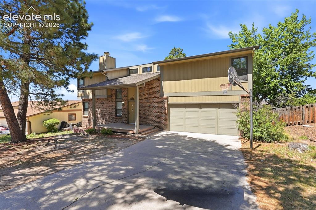 Image 1 of 50: Split-level residence featuring a two-car garage with panel doors, brick ac