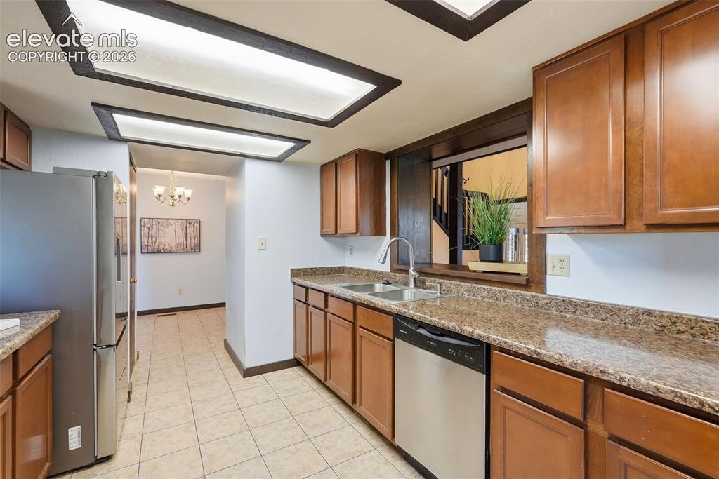Image 10 of 50: Kitchen featuring wood cabinetry, mottled countertops, stainless steel sink