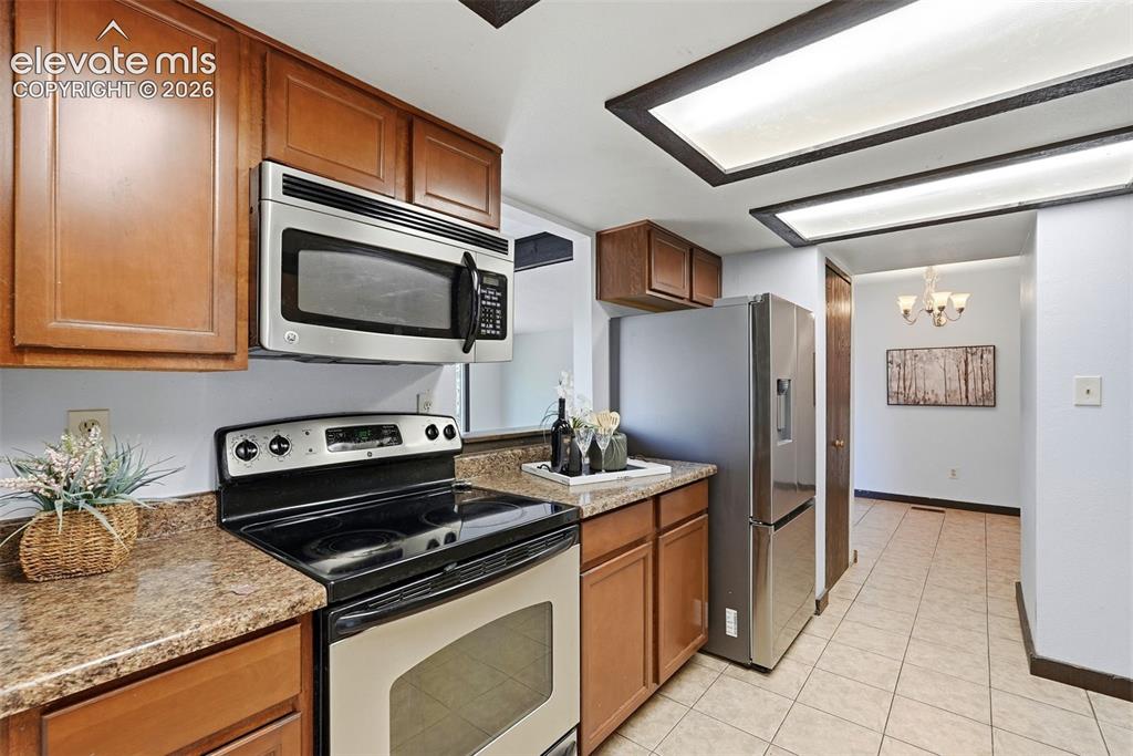 Image 11 of 50: Kitchen featuring wood cabinetry, stainless steel range, stainless steel mi