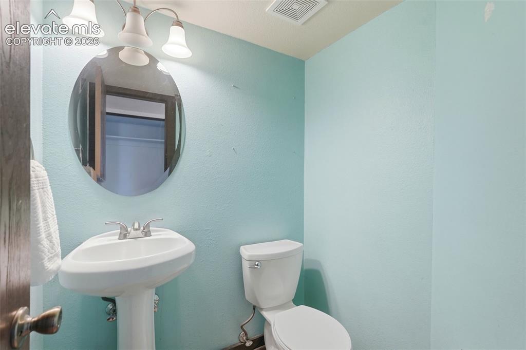 Image 20 of 50: Powder room featuring a pedestal sink, oval mirror, and a two-bulb vanity l