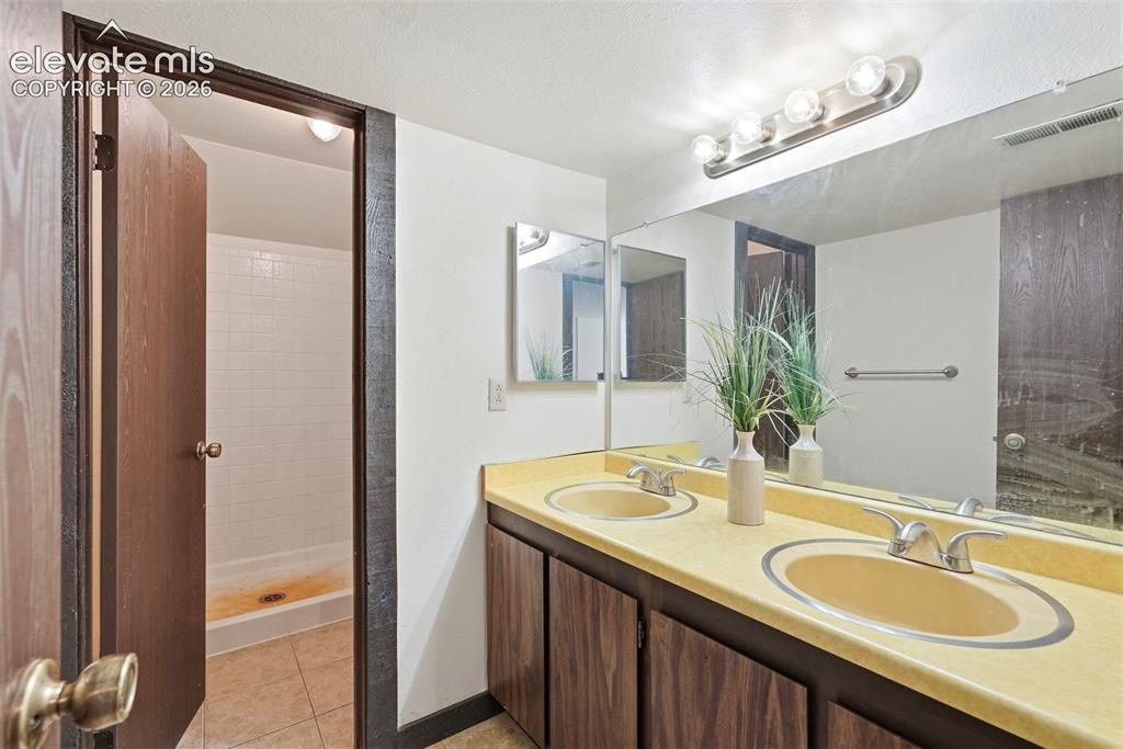 Image 24 of 50: Bathroom featuring a dual vanity with integrated sinks and a large wall-mou
