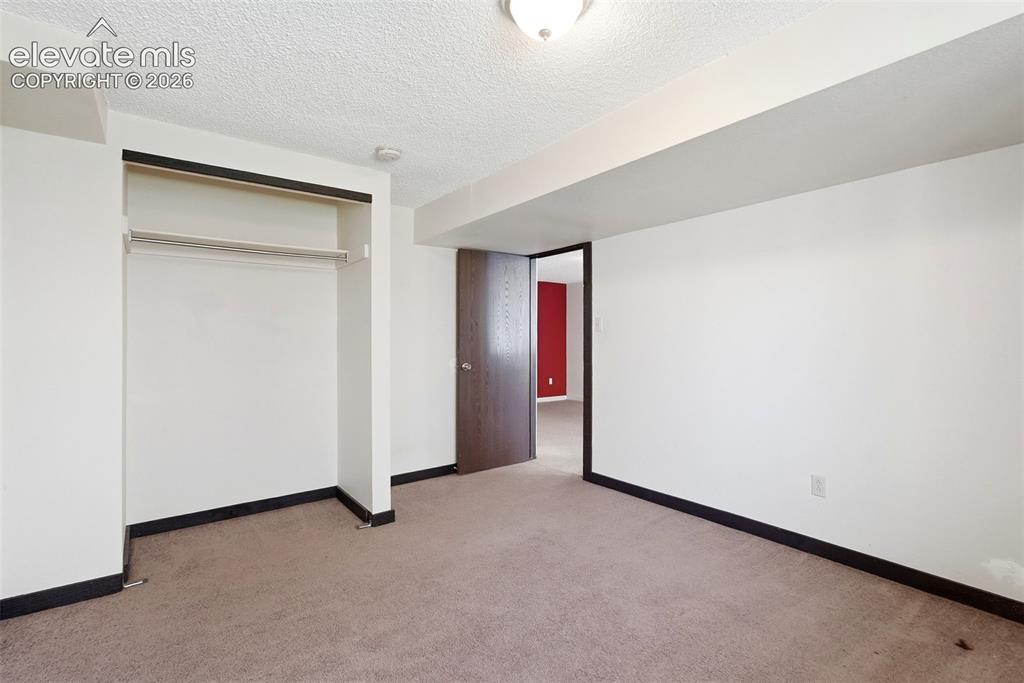 Image 27 of 50: Room featuring neutral carpet flooring, white walls, dark trim, an open clo