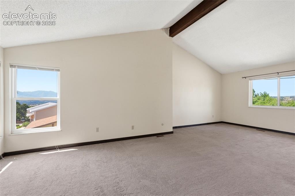 Image 30 of 50: Spacious room featuring vaulted ceilings with an exposed beam, multiple lar