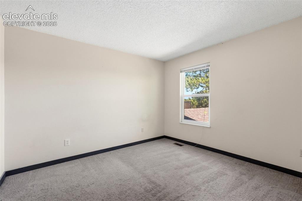 Image 34 of 50: Bright room featuring a single window with blinds, light-colored walls, and