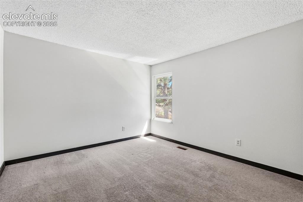 Image 36 of 50: Room featuring light gray walls, gray carpet flooring, black baseboards, an