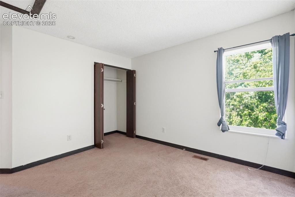 Image 39 of 50: Bright room featuring a large window, neutral carpet flooring, white walls,