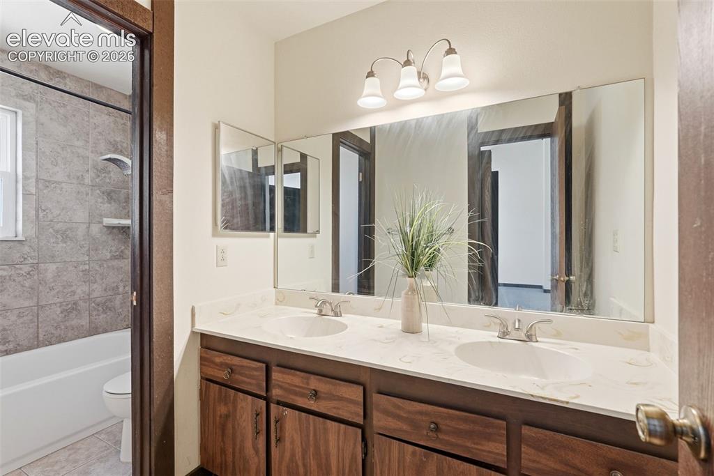 Image 41 of 50: Bathroom featuring a double vanity with integrated sinks, a wide vanity mir