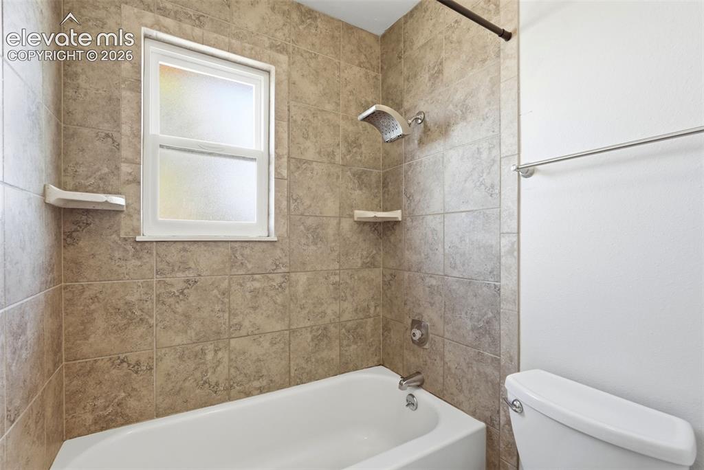 Image 42 of 50: Tub-shower combination featuring textured tile surround, built-in shelving,