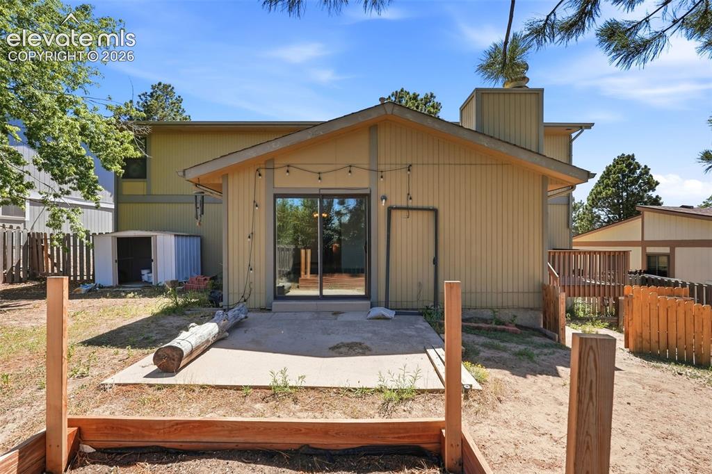 Image 46 of 50: Rear exterior featuring a patio, sliding glass door entry, and a wood-frame