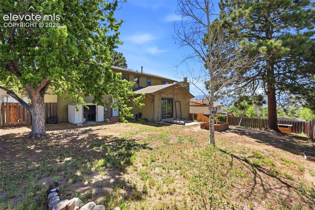 Image 47 of 50: Expansive backyard featuring mature trees, a wood privacy fence, and a stor