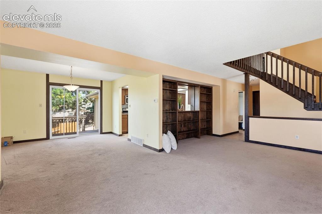 Image 5 of 50: Expansive interior space featuring light-colored walls and carpeted floorin
