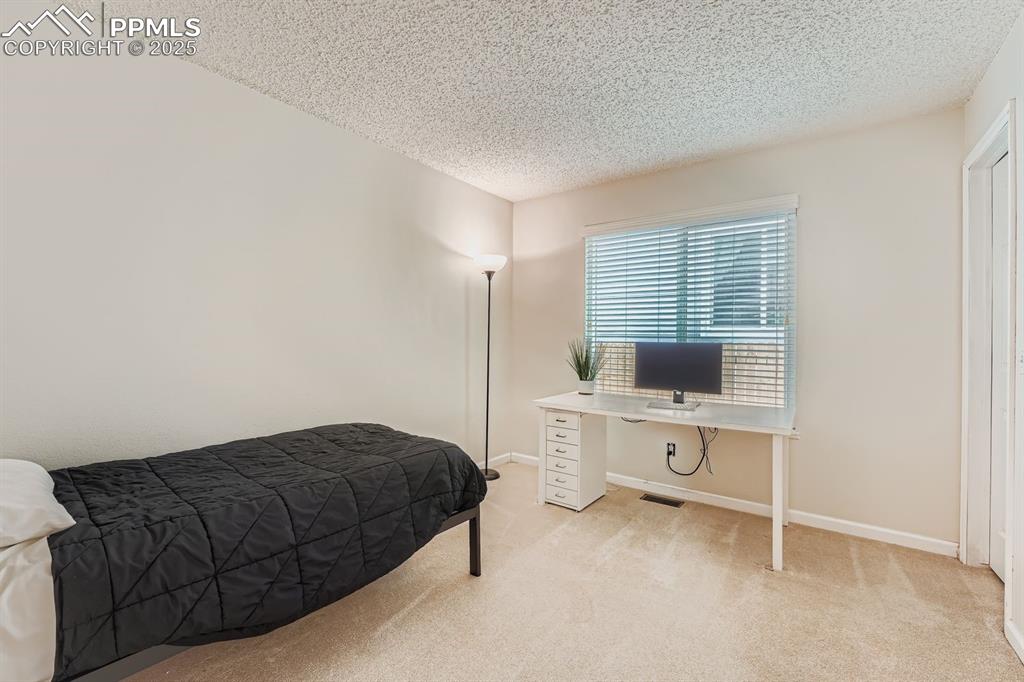 Image 15 of 32: Carpeted bedroom with a textured ceiling and an office area