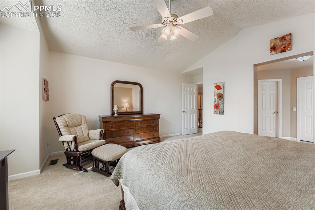Image 18 of 32: Bedroom with light carpet, vaulted ceiling, a textured ceiling, and a ceili