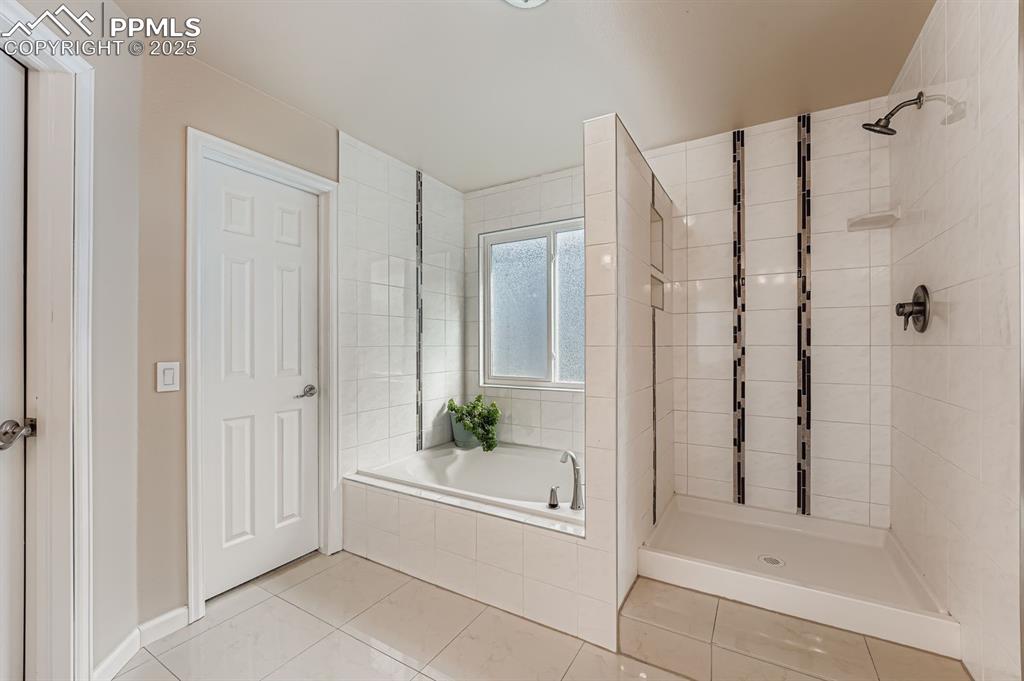 Image 21 of 32: Full bathroom with a bath, a stall shower, and light tile patterned floors