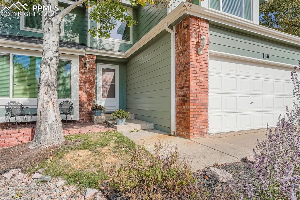 Image 3 of 32: Doorway to property featuring a garage and brick siding