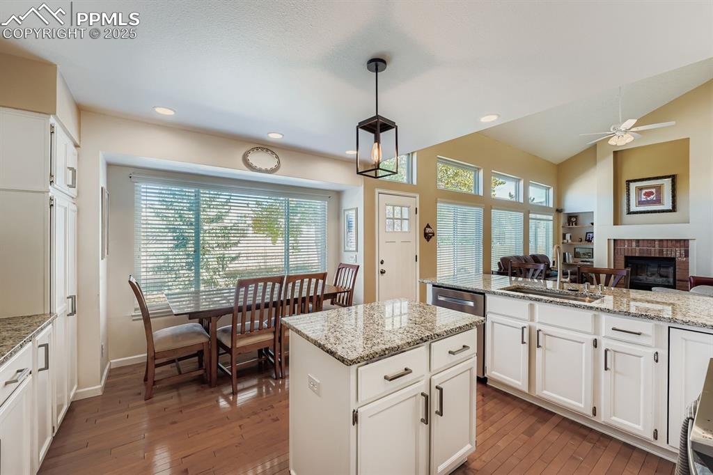 Image 4 of 32: Kitchen with white cabinetry, light stone countertops, a glass covered fire