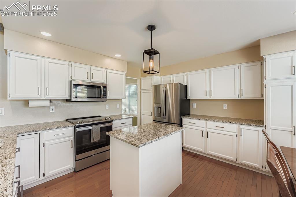 Image 6 of 32: Kitchen featuring stainless steel appliances, white cabinetry, a center isl