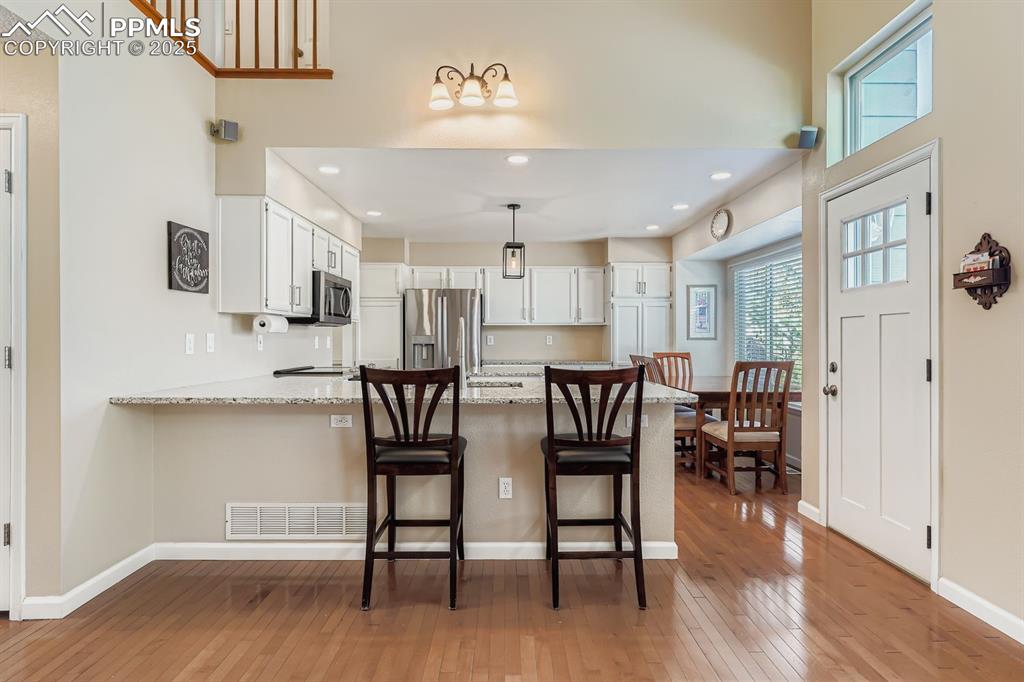 Image 7 of 32: Kitchen featuring white cabinets, recessed lighting, light wood-type floori