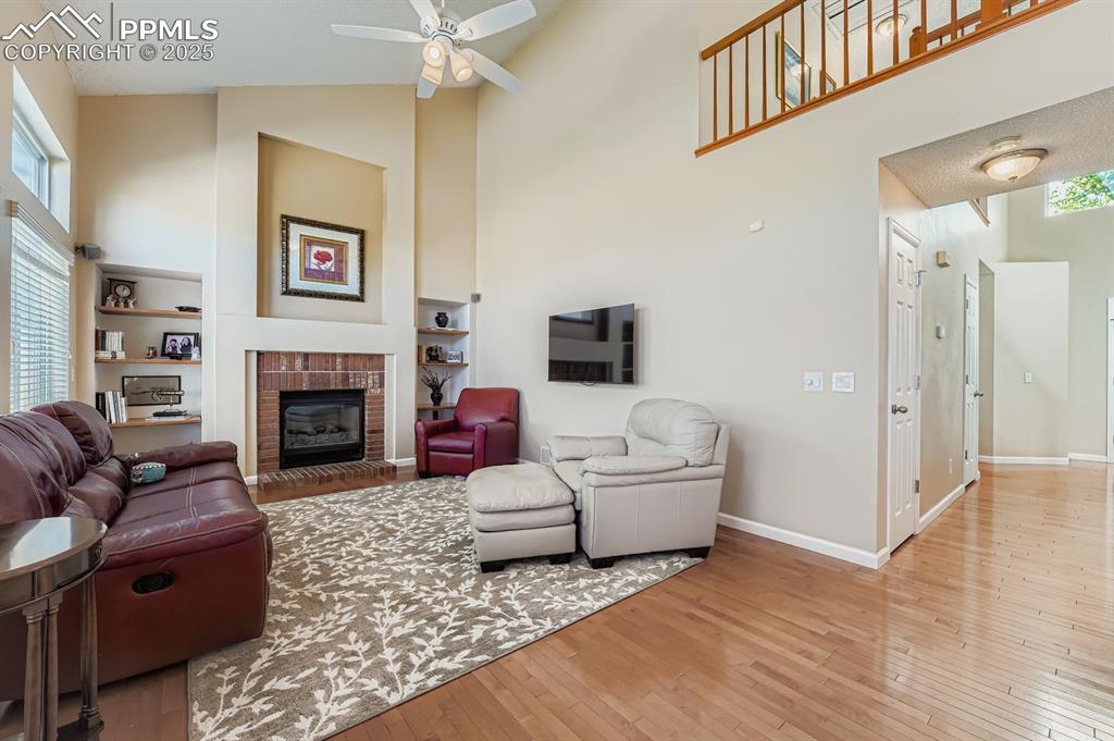 Image 8 of 32: Living room featuring high vaulted ceiling, light wood-style floors, a fire
