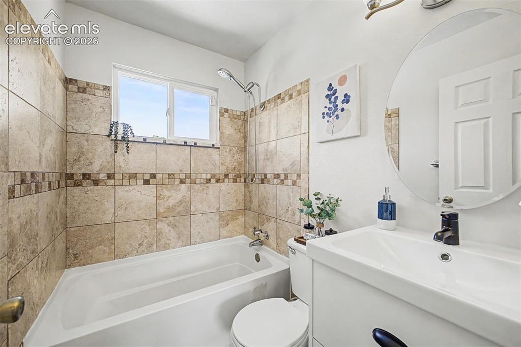 Image 13 of 37: Bathroom featuring a tiled shower surround with decorative accent band, a b