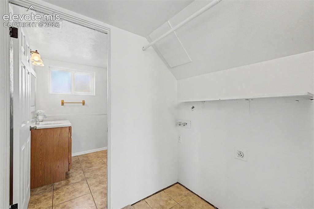 Image 16 of 37: Laundry area with wall-mounted shelving and utility connections