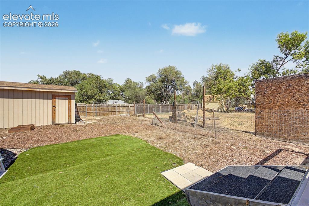 Image 22 of 37: Expansive backyard featuring artificial turf, a large shed and fencing.