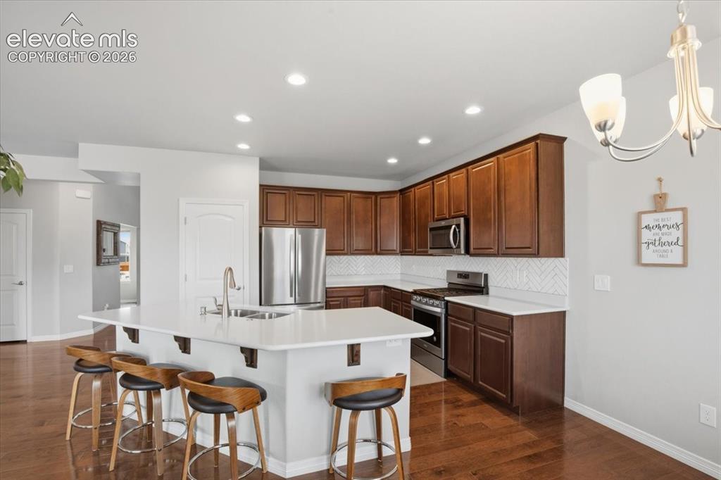 Image 10 of 31: Spacious kitchen featuring an island with seating, dark wood cabinetry, whi
