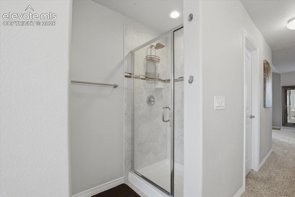 Image 18 of 31: Enclosed shower with glass door and tile surround featuring a decorative ac