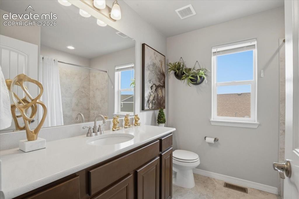 Image 20 of 31: Dark wood-finish vanity with an undermount sink, light-toned countertop, an