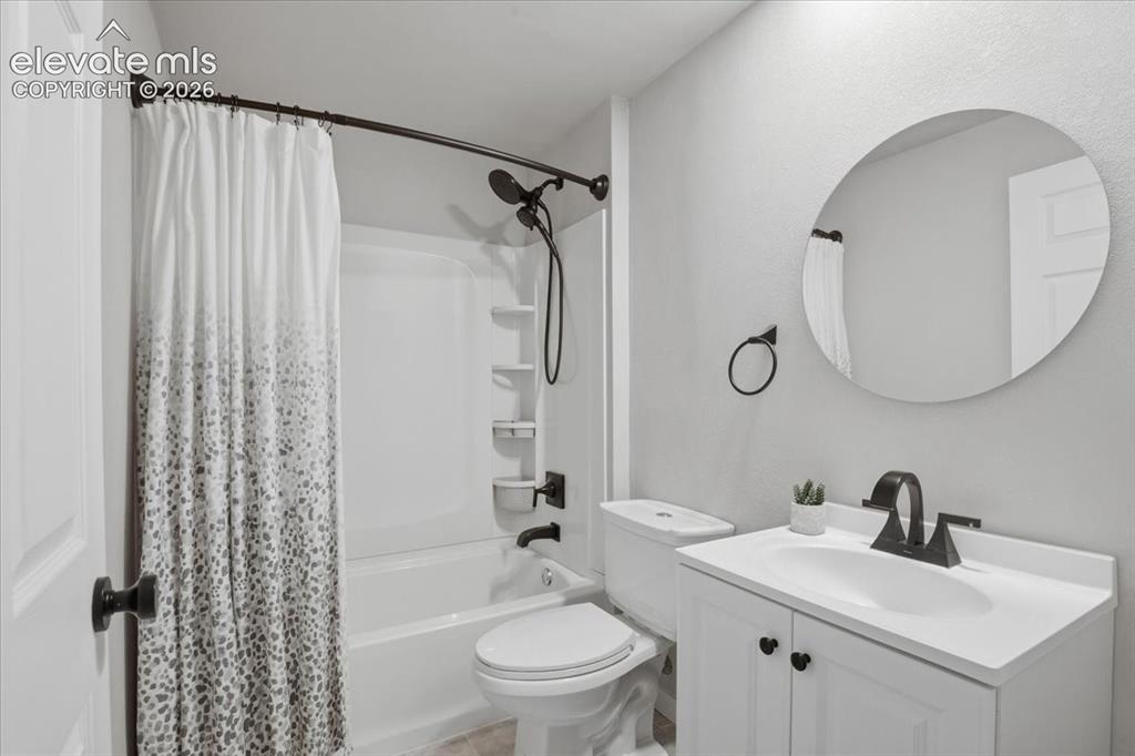 Image 23 of 31: White vanity with integrated sink, black faucet, and circular mirror