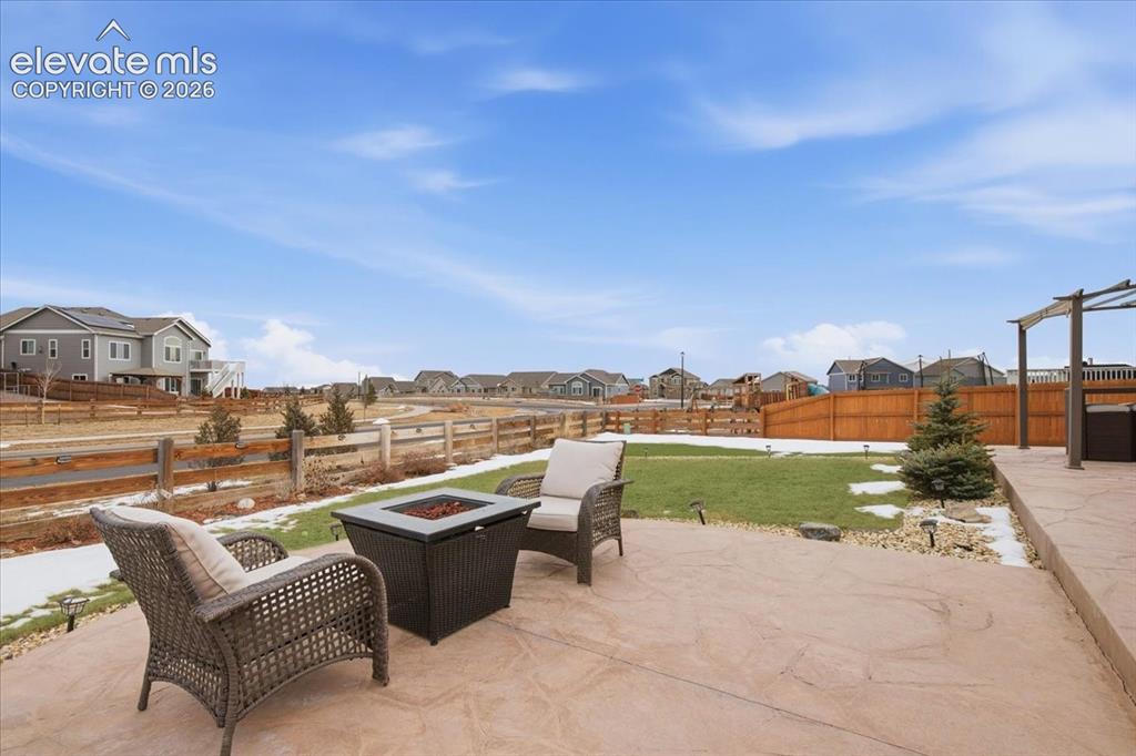 Image 27 of 31: Stamped concrete patio with integrated fire pit, expansive lawn, and wooden