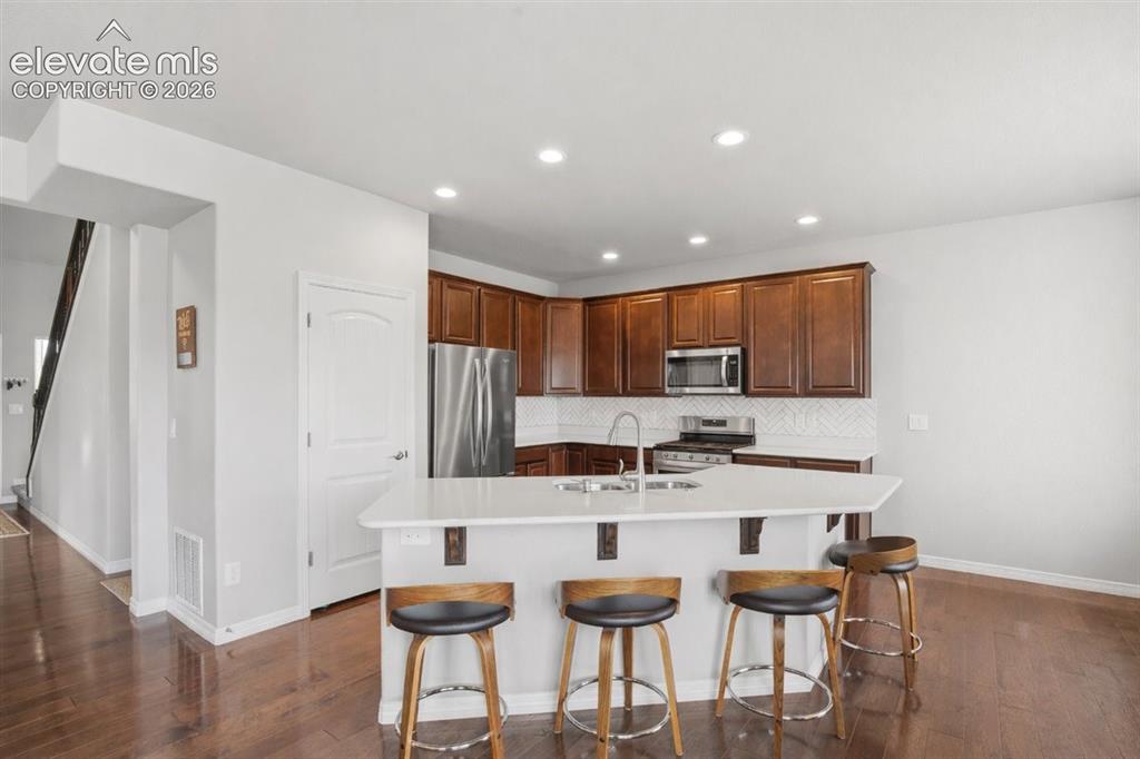 Image 4 of 31: Kitchen featuring warm wood cabinetry, stainless steel appliances, a white 