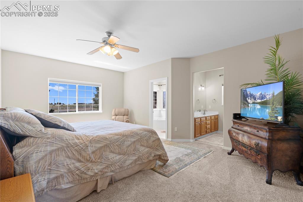 Image 11 of 45: Bedroom with light carpet, ensuite bath, and a ceiling fan