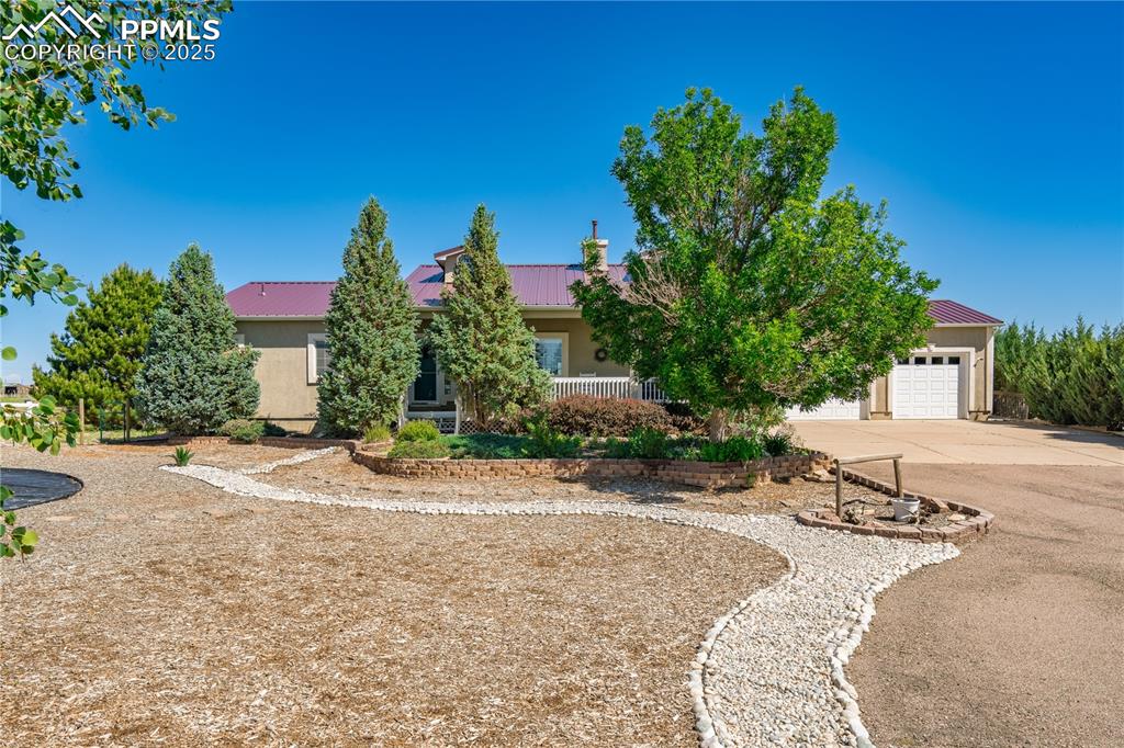Image 3 of 45: View of property hidden behind natural elements with driveway, an attached