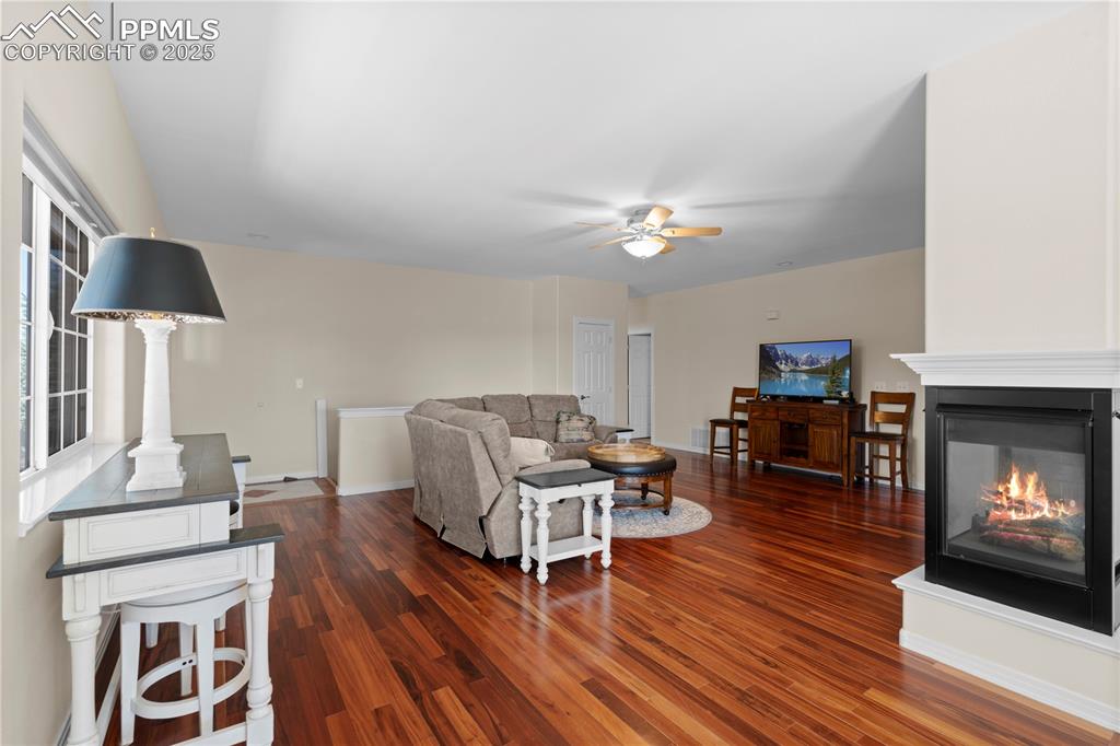 Image 7 of 45: Living area featuring dark wood finished floors, ceiling fan, and a multi s