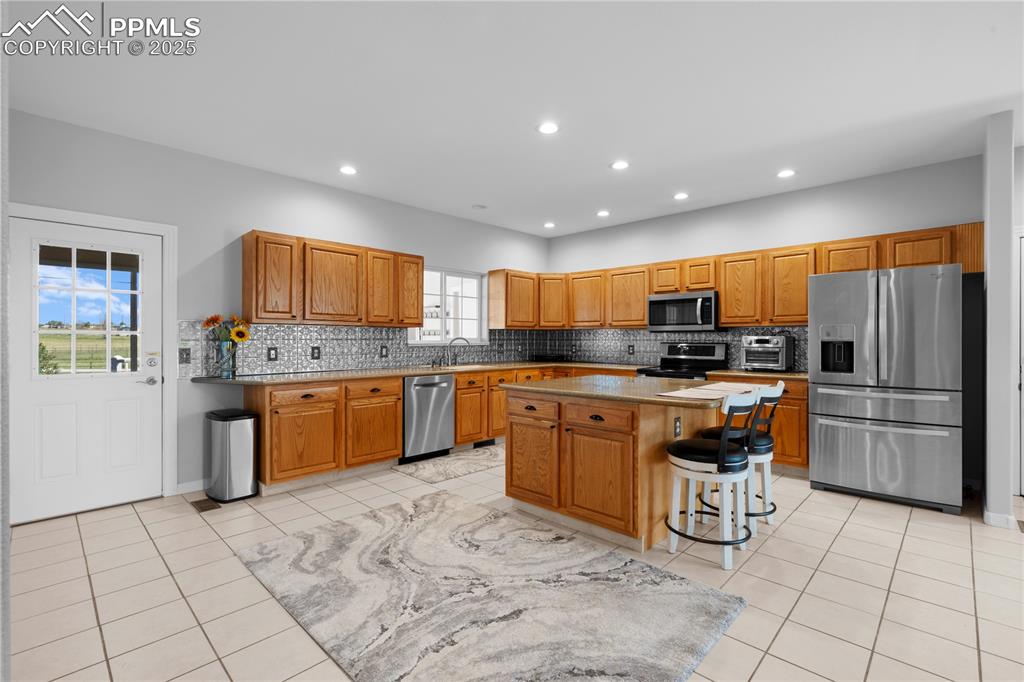 Image 9 of 45: Kitchen featuring stainless steel appliances, backsplash, recessed lighting