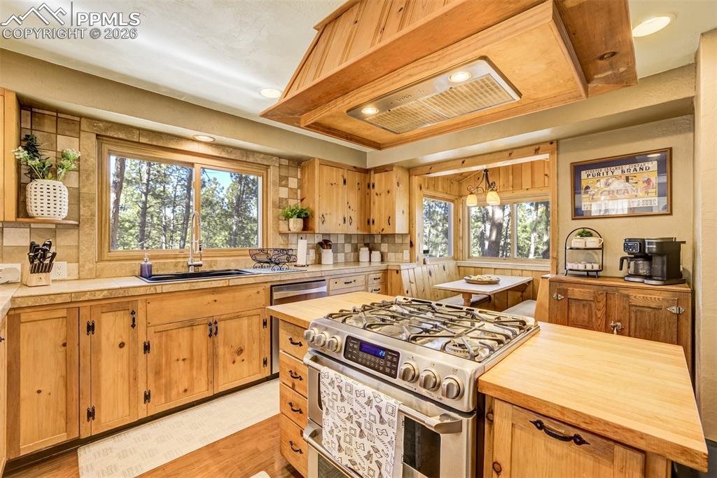 Image 14 of 50: Kitchen featuring stainless steel gas stove, a center island, open shelves,