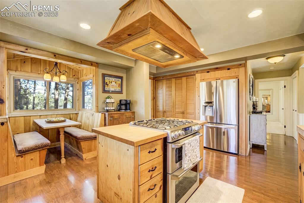 Image 17 of 50: Kitchen with stainless steel appliances, gas range and island range hood, b