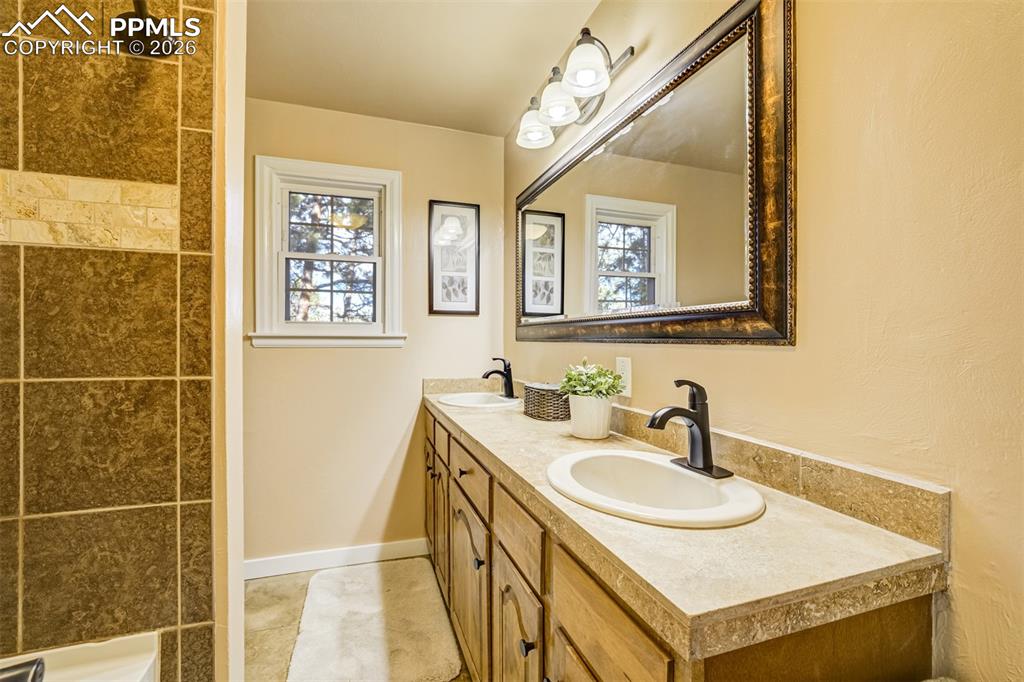 Image 19 of 50: Main level full bathroom with double vanity and a shower
