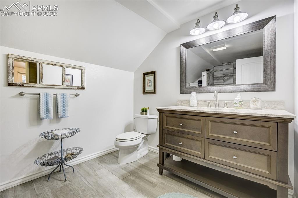 Image 27 of 50: Full bath with vanity, light wood-style floors, vaulted ceiling, and a tub/