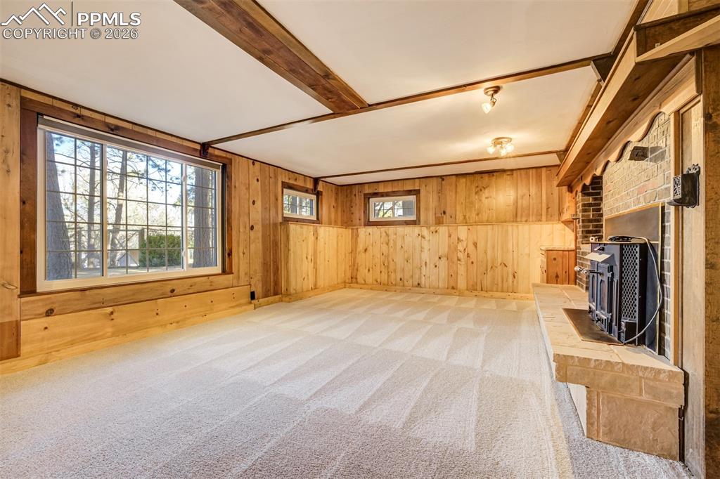 Image 32 of 50: Family room featuring walkout, new carpet, wood walls, a brick wood burning