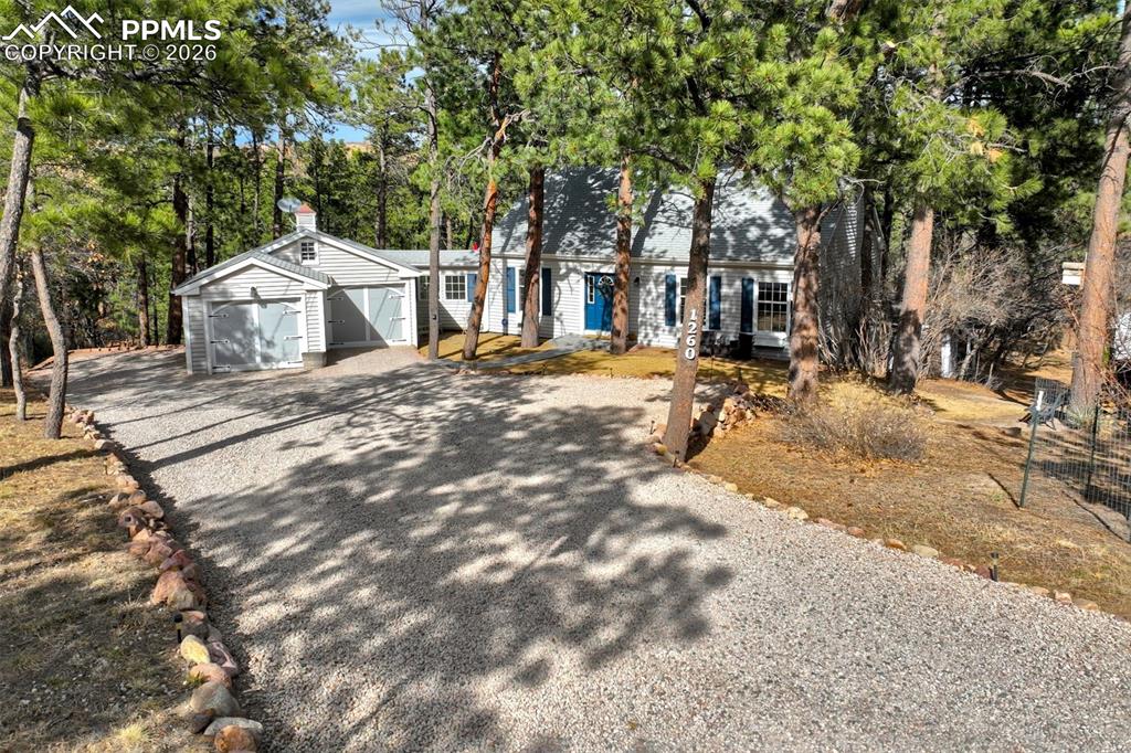 Image 47 of 50: View of front of house with driveway and view of wooded area