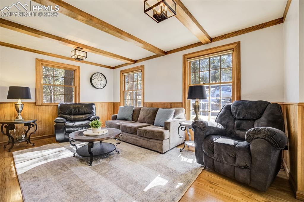 Image 7 of 50: Main level living area with wood wainscoted wall, built in features, a fire